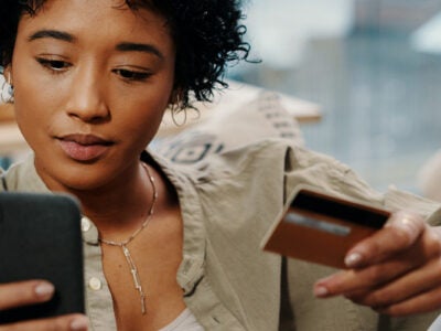 Woman holding phone and credit card.