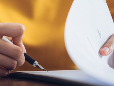 Person filing out documents with a pen.