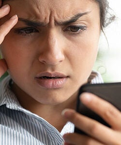 woman looking worried at her phone