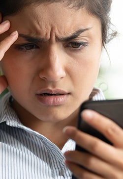 woman looking worried at her phone