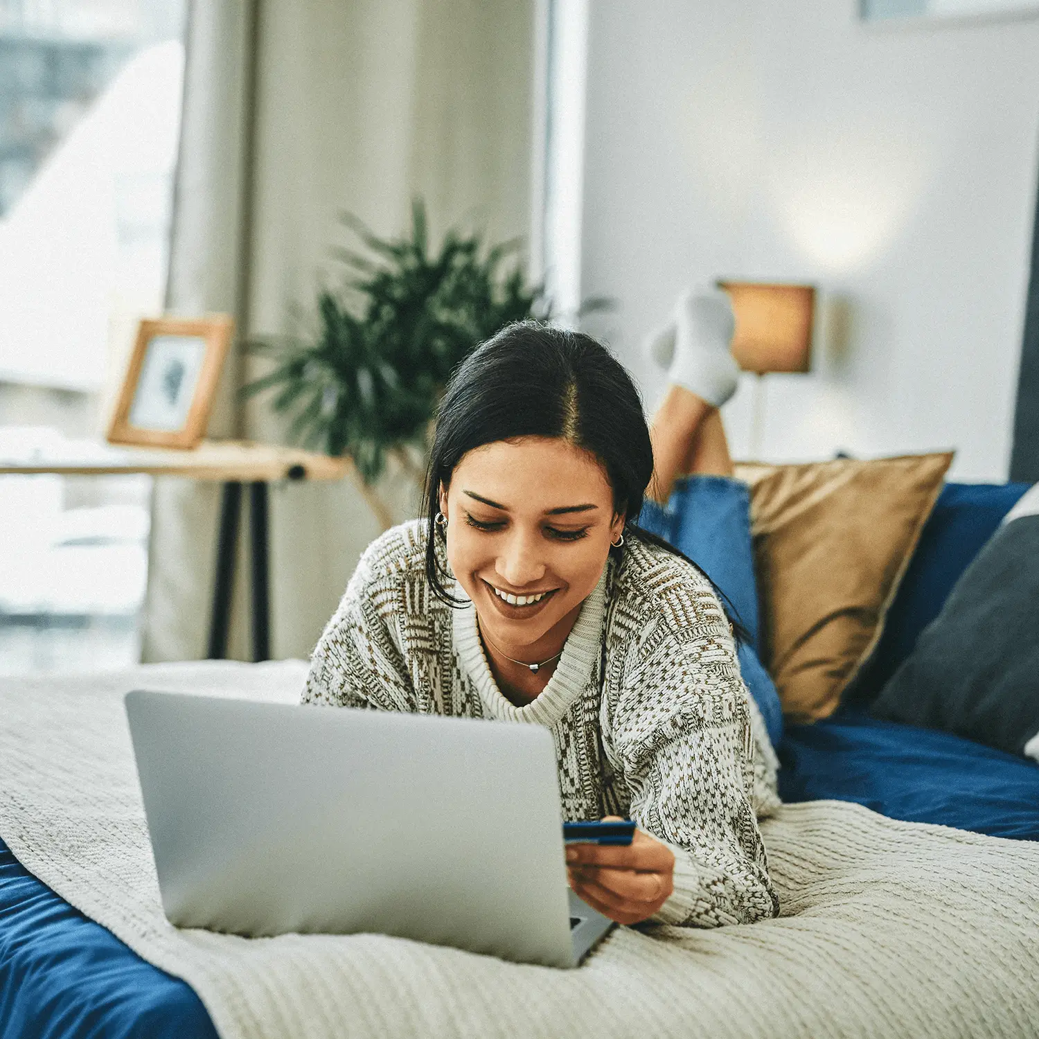 A woman in bed shopping online with a credit card.