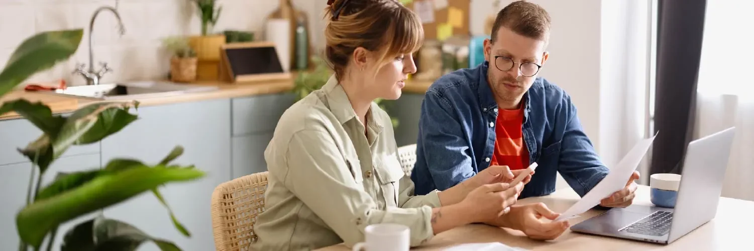 Husband and wife at their kitchen table looking at their credit reports.