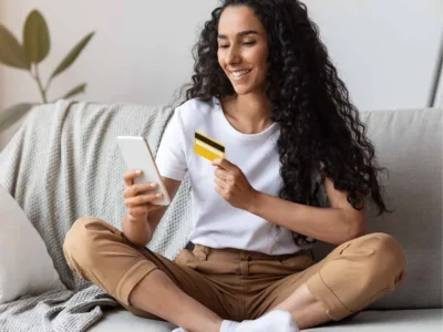 A woman on her couch making a personal loan payment with her credit card.