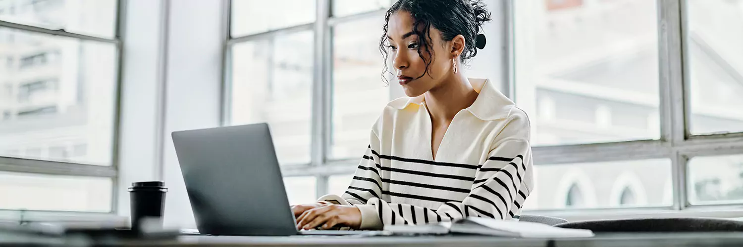 Photo of woman monitoring her credit on a laptop.